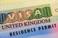 UK Biometrical Residence Permit BRP card placed on top of UK tourist visa sticker in a passport. Macro photo