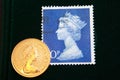 UK blue stamp with portrait of Elizabeth II and 1980 Australian Gold sovereign on black background