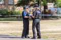 Police officers talking in front of crime scene tape