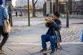 A busker playing a trumpet on a cold but sunny day Royalty Free Stock Photo