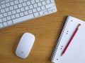 UK, October 2019: Apple mac wireless mouse and keyboard on wooden desk with notepad and pencil