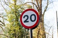 A UK Traffic sign showing.a 20 mph maximum speed limit with a red and white warning circle