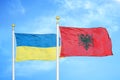 Ukraine and Albania two flags on flagpoles and blue sky