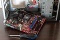 Ukraine - April 25, 2020: Disconnected motherboard of computer and Phillips screwdriver near the case on brown background.