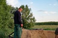 Ukraine, Chernivtsi, 10 08 2019 Man in work clothes, red gloves and respirator standing on the barrel sprayer tank and