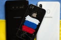 Ukraine Dnepr 09.03.2022 Broken apple iPhone 4 with a painted Russian flag and a Samsung phone on the background of the flag of