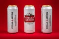 Ukraine. Dnipro. 20 march 2023: Three white can of great Belgium beer Stella Artois on red background