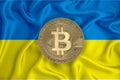 Ukraine flag, bitcoin gold coin on flag background. The concept of blockchain, bitcoin, currency decentralization in the country.