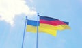 Ukraine and Germany, flags waving against blue sky Royalty Free Stock Photo