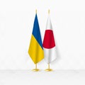 Ukraine and Japan flags on flag stand, illustration for diplomacy and other meeting between Ukraine and Japan