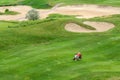 Ukraine, Kharkiv, June 2021. Green grass and holes on the golf course. Golf field on a sunny summer day. A group of people are