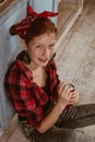 Ukraine. Kiev - 11.25,2019 A cute red-haired girl with freckles, dressed in a red bandana and a checkered shirt, drinks Coca-Cola
