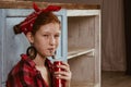 Ukraine. Kiev - 11.25,2019 A cute red-haired girl with freckles, dressed in a red bandana and a checkered shirt, drinks Coca-Cola