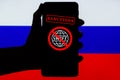 Ukraine, Kiev - February, 23 2022: Silhouette of black hand holding mobile with crossed out SWIFT logo and Russian flag