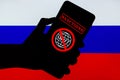 Ukraine, Kiev - February, 23 2022: Silhouette of black hand holding mobile with crossed out SWIFT logo and Russian flag