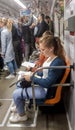 Ukraine, Kiev - October 6, 2019: Portrait of a young woman tourist in a subway car reads a newspaper. Beautiful girl reads a book