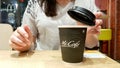 Ukraine, Kiev - September 09, 2019: A girl covers a black plastic paper lid with a hot black coffee maker in McDonalds, McCafe