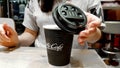 Ukraine, Kiev - September 09, 2019: A girl covers a black plastic paper lid with a hot black coffee maker in McDonalds, McCafe