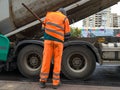 Ukraine, Kiev - September 22, 2019: Worker in orange overalls, bright work clothes with reflectors. A builder with a shovel stands