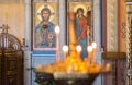 Interior Pyrohoshcha Dormition of the Mother of God Church. Unfocused glowing candles with icons on background.