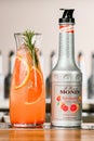 UKRAINE, KYIV - MARCH 11, 2021: Close-up of bottle of Ruby Grapefruit Syrup by Monin and glass carafe of cocktail with Royalty Free Stock Photo