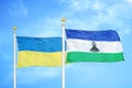 Ukraine and Lesotho two flags on flagpoles and blue sky