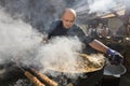 UKRAINE, LUTSK - June 5, 2019: Man is cooking a fresh mussels in shells in large metallic grill pan on a food fest.