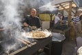 UKRAINE, LUTSK - June 5, 2019: Man is cooking a fresh mussels in shells in large metallic grill pan on a food fest.