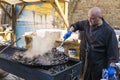 UKRAINE, LUTSK - June 5, 2019: Man is cooking a fresh mussels in shells in large metallic grill pan on a food fest.