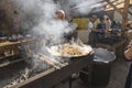 UKRAINE, LUTSK - June 5, 2019: Man is cooking a fresh mussels in shells in large metallic grill pan on a food fest.