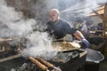 UKRAINE, LUTSK - June 5, 2019: Man is cooking a fresh mussels in shells in large metallic grill pan on a food fest.