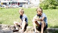 Ukraine, summer, 5 June 2023. Two boy friends are sitting on the curb in the city center against the background of shops and cars Royalty Free Stock Photo