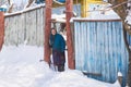 Ukraine, Svirzh, St. Lesnaya - January 13, 2019: Old grandmother stands near her house in the village in winter Royalty Free Stock Photo