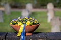 Ukraine war: flower bowl in memory of fallen soldiers with pansies in Ukrainian colors and blue and yellow ribbon on a cemetery.