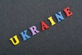 Ukraine word on black board background composed from colorful abc alphabet block wooden letters, copy space for ad text