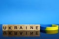 Ukraine word made of wooden letters and a yellow-blue bracelet on a mirror surface