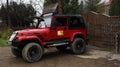 Ukraine, Yaremche - November 20, 2019: a red Jeep Wrangler 4.0i V6 SUV is parked on a rural road near a house in a small town of