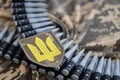 Ukrainian army symbol on machine gun belt lies on ukrainian pixeled military camouflage