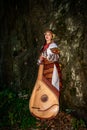 Ukrainian bandurist in national dress stands near a rock