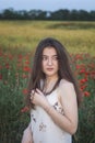 Ukrainian beautiful girl in a field of poppies and wheat. Outdoor portrait. Collects poppies in summer fields. A symbol of the Royalty Free Stock Photo