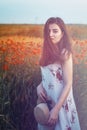 Ukrainian beautiful girl in a field of poppies and wheat. Outdoor portrait. Collects poppies in summer fields. A symbol of the Royalty Free Stock Photo