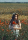 Ukrainian beautiful girl in a field of poppies and wheat. Outdoor portrait. Collects poppies in summer fields. A symbol of the Royalty Free Stock Photo