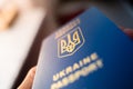 Ukrainian biometric passport in hand close-up on a blurred background. Coat of arms of Ukraine in the form of a trident. Blue Royalty Free Stock Photo
