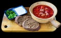 Ukrainian Borscht with beef and black bread with greens on wooden chop on black background side view