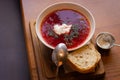 Ukrainian borsht with bread on wooden table. Red soup with cream and bread. Ukrainian traditional food. Homemade borscht.