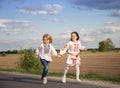 Ukrainian children, boy and girl of 6-7 years old in national embroidered clothes run forward to victory
