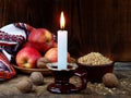 Ukrainian Christmas concept for greeting card. Composition of burning candle, apples, walnuts, wheat on wooden background. Copy sp Royalty Free Stock Photo