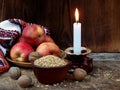 Ukrainian Christmas concept for greeting card. Composition of burning candle, apples, walnuts, wheat on wooden background. Copy sp