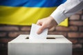 A Ukrainian citizen\'s hand casts a vote into the ballot box against the backdrop of the Ukrainian flag