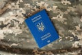 Ukrainian civil foreign passport on military camouflage pixel background.